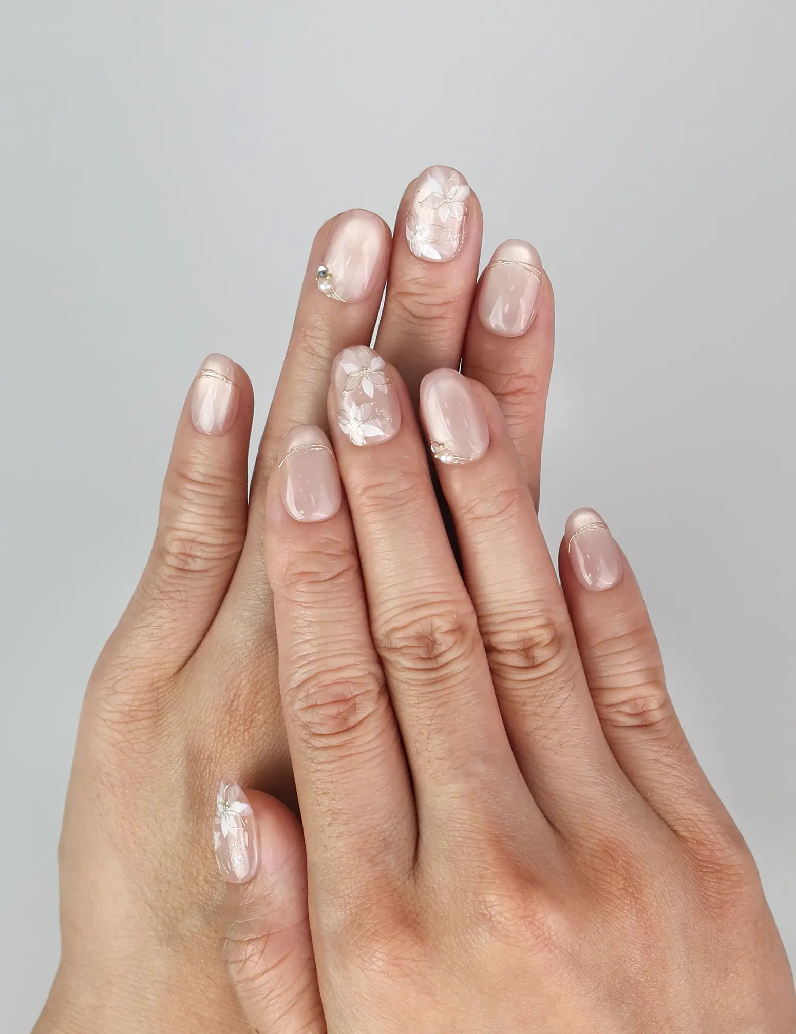 Model wearing Naillover Lucid Petals handmade Singapore press on nails in pink with gold floral and pearl accents.