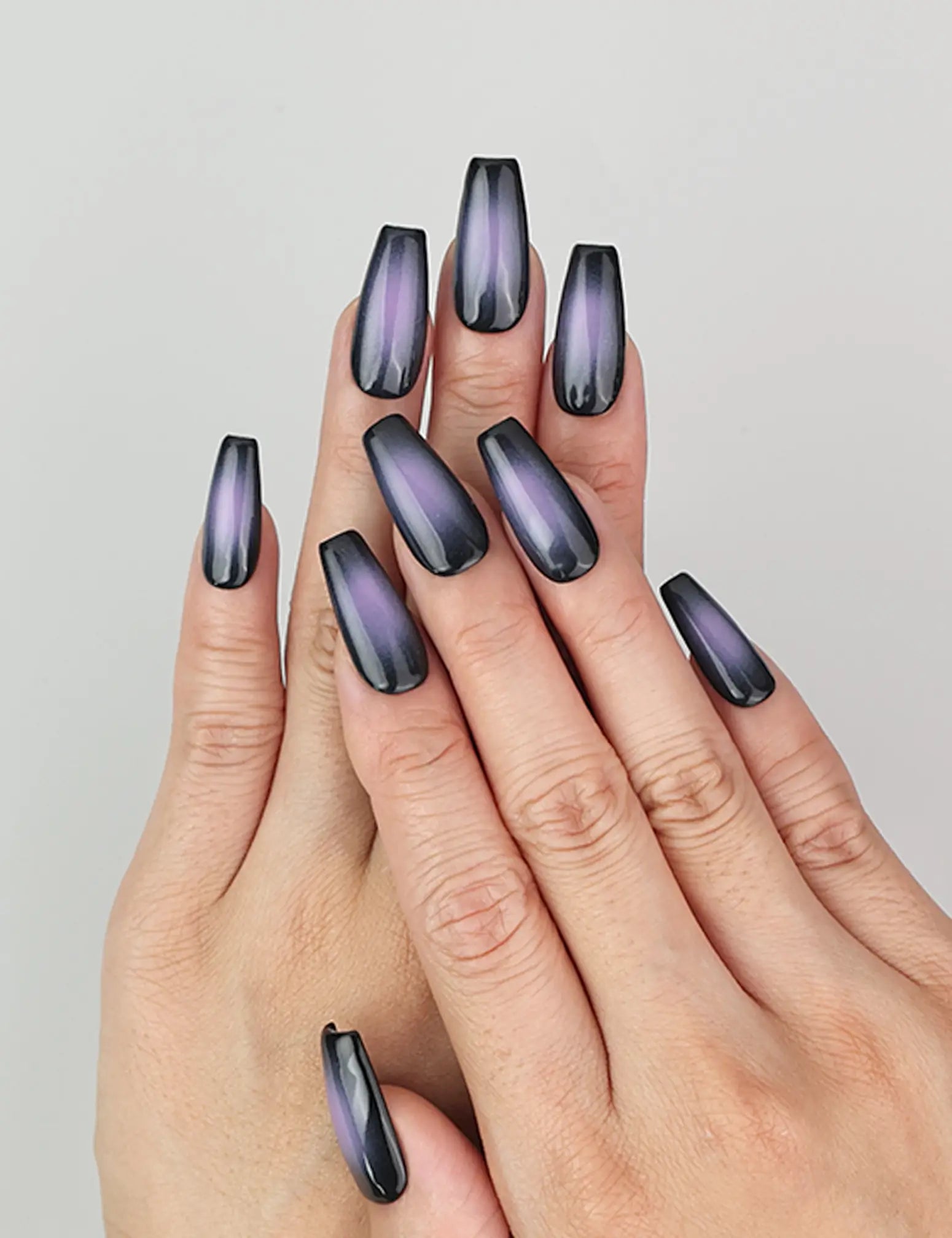 Hand wearing Naillover Lunar Eclipse press on nails, black to purple ombre design in natural lighting