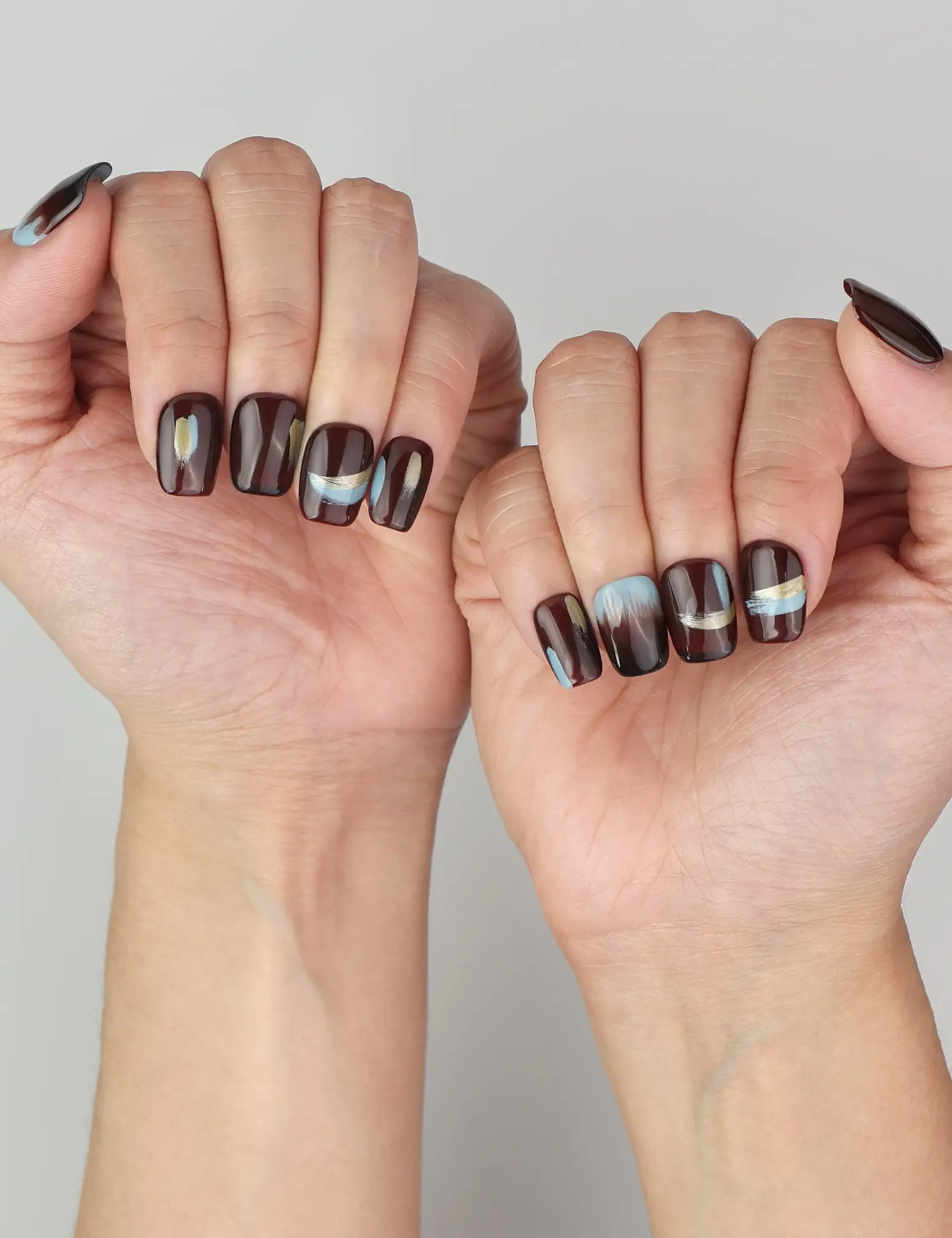 Close-up of hand wearing Naillover Mystic Maroon press on nails Singapore, showing glossy burgundy with striking blue and gold details