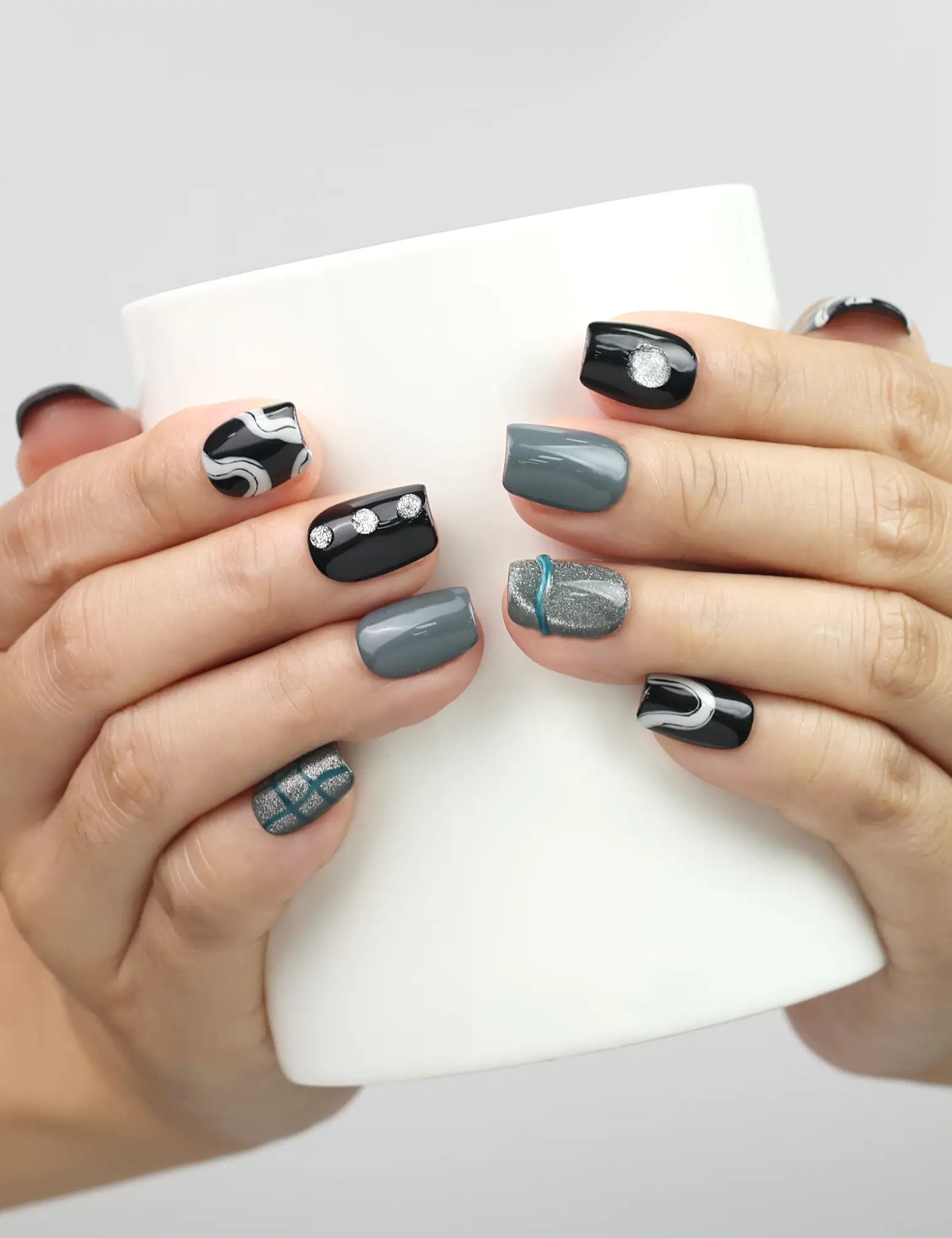 Model holding a cup while showing Naillover Mystic Swirl handmade Singapore press on nails in marble black and grey with glitter details.