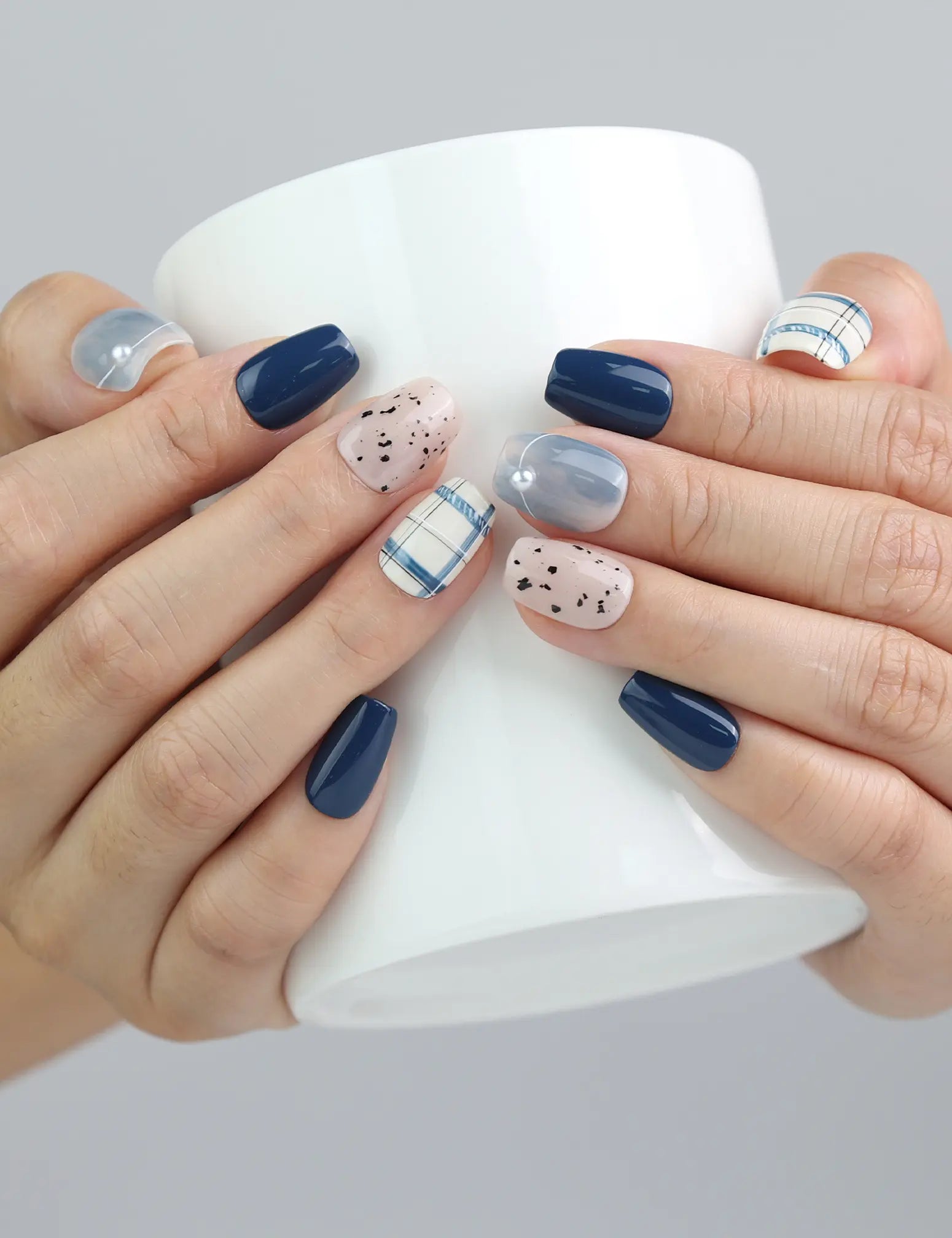 Hand holding a cup while wearing Naillover Nautical Stripe nails, displaying playful stripes and nautical elegance.