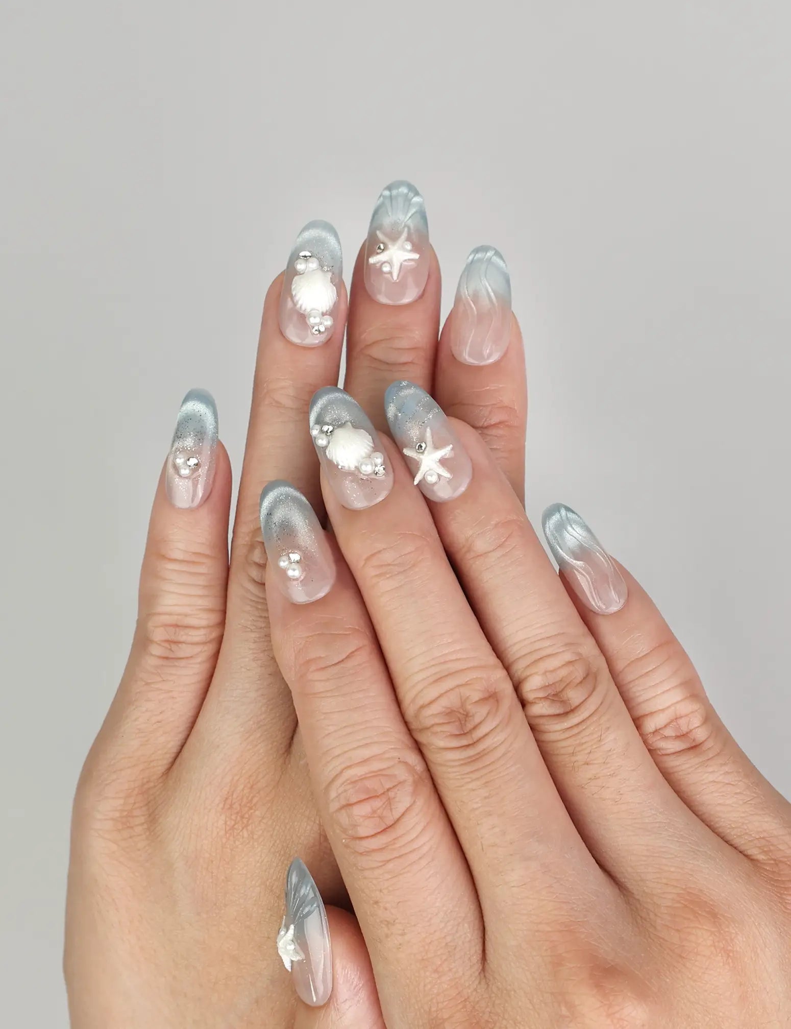 Hand wearing Naillover Ocean Whisper Singapore press on nails with blue gradient and 3D starfish details