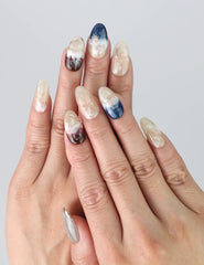 Model wearing Oceanic Essence press on nails by Naillover, showcasing blue marble textures and glossy finish.