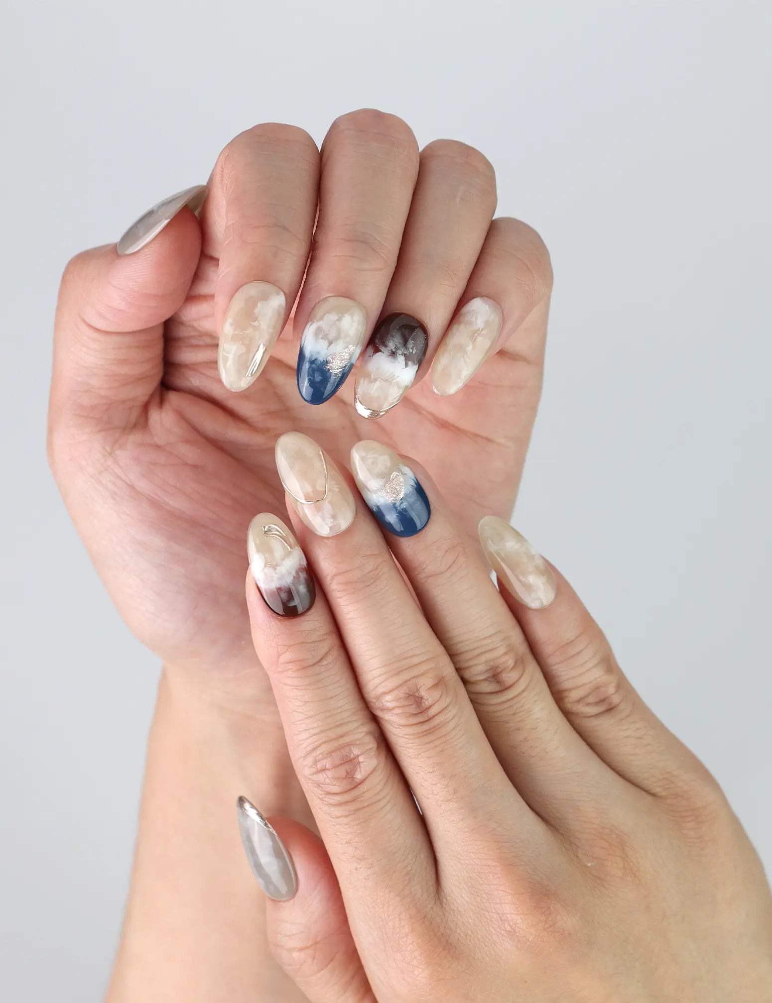 Close-up of Oceanic Essence nails on hand, highlighting shimmering blue tones and delicate handcrafted gold accents.