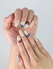 Close-up of Oceanic Essence nails on hand, highlighting shimmering blue tones and delicate handcrafted gold accents.