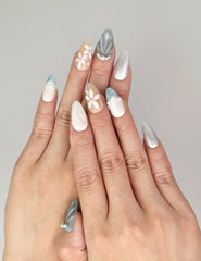 Naillover Oceanic Floral Breeze handmade press on nails styled on hand with blue-green tones, floral accents, and pearlescent textures.