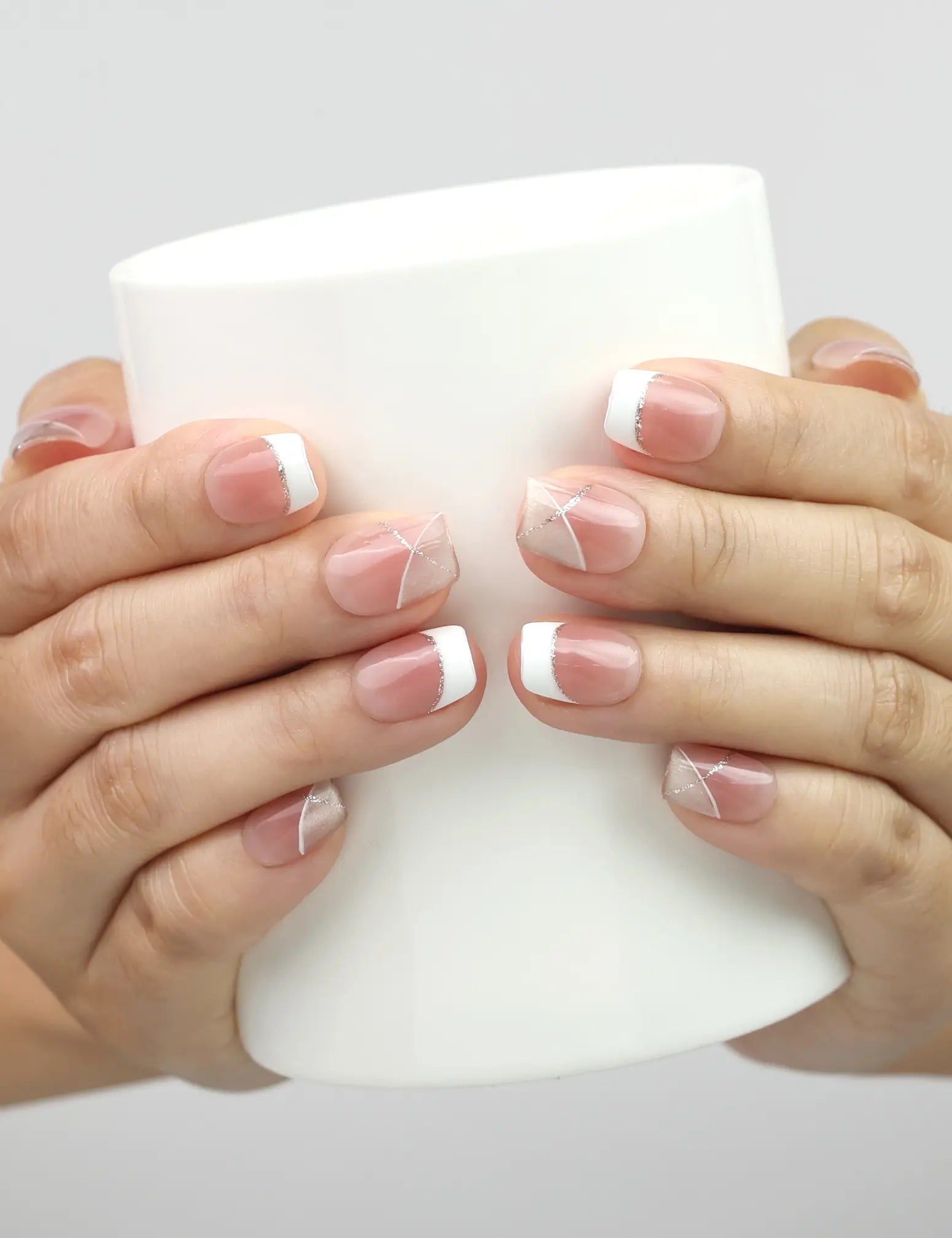 Model holding a cup while wearing Naillover Opal Scheme handmade Singapore press on nails with silver line accents.