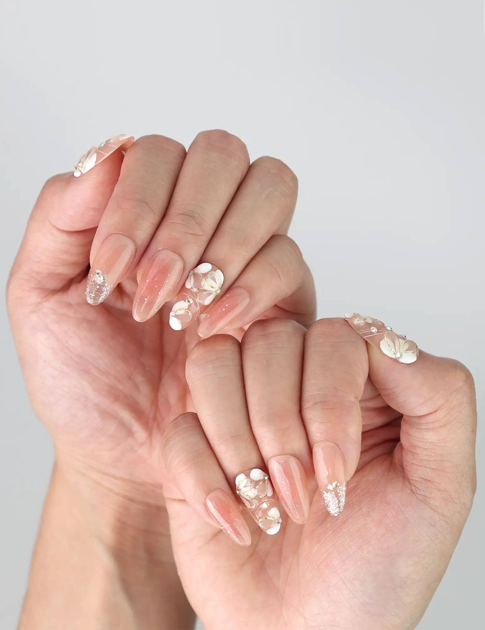 Peachy Glow handmade press on nails shown on hand with relaxed pose, highlighting elegant floral design