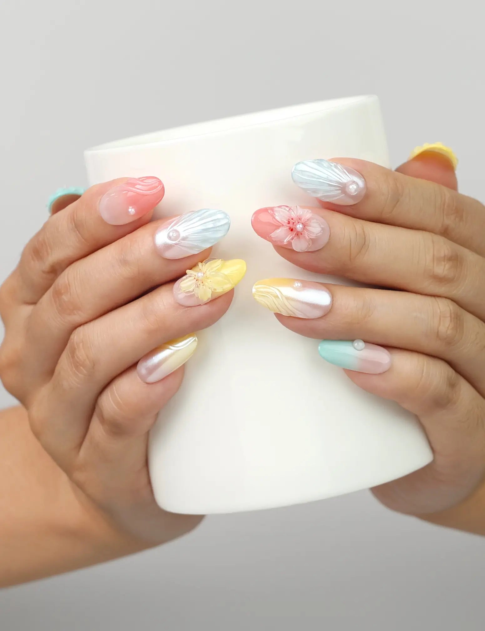 Model holding a cup wearing Naillover Pearl Bloom Fantasy 3D Summer Nails with handmade gradient and pearl details.