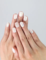 Hand wearing Naillover Pearl Haze press on nails with white 3D flowers and pearl accents, ideal for weddings or formal events.