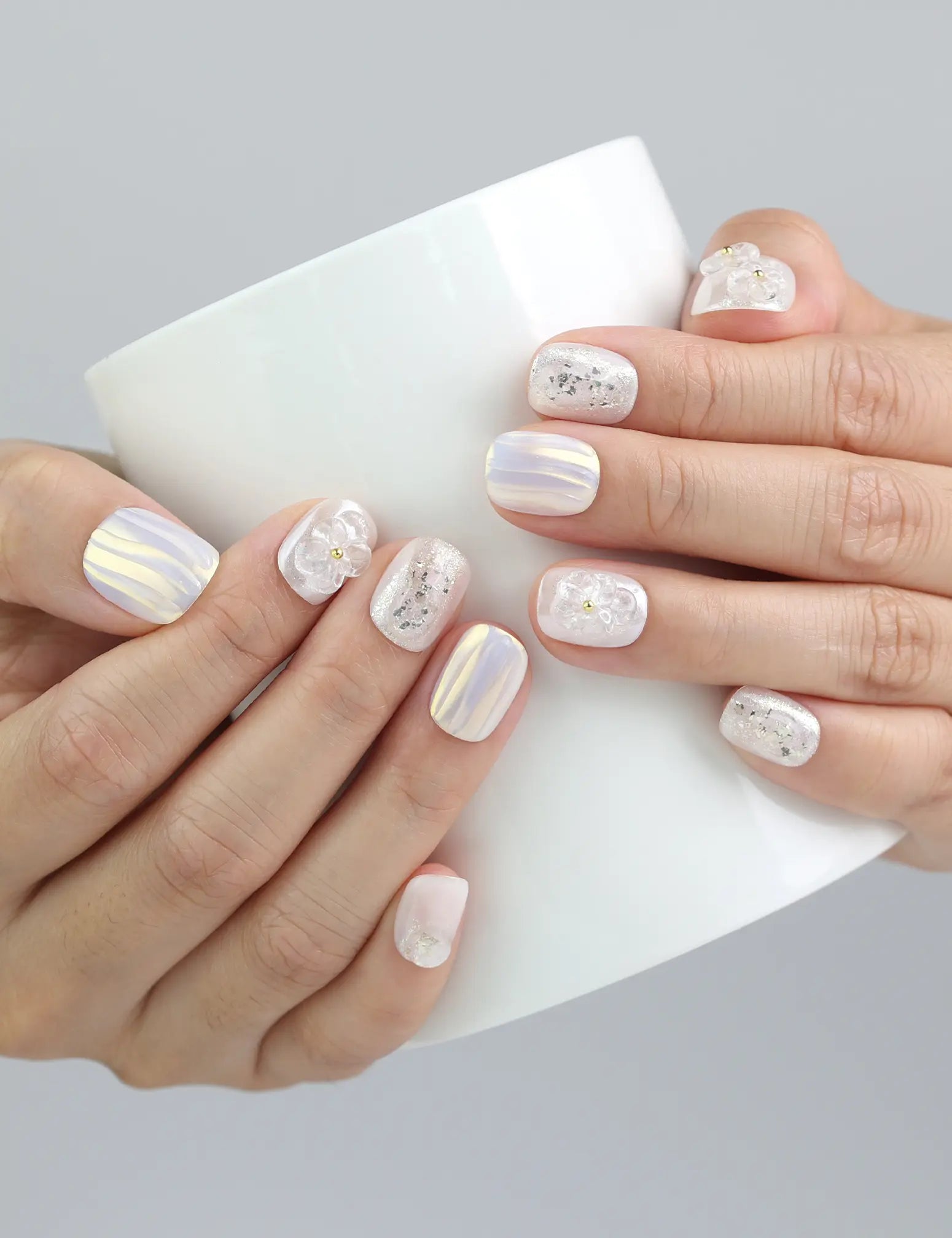 Hand holding a cup while wearing Pearl Haze press on nails with 3D floral elements and delicate pearl touches.