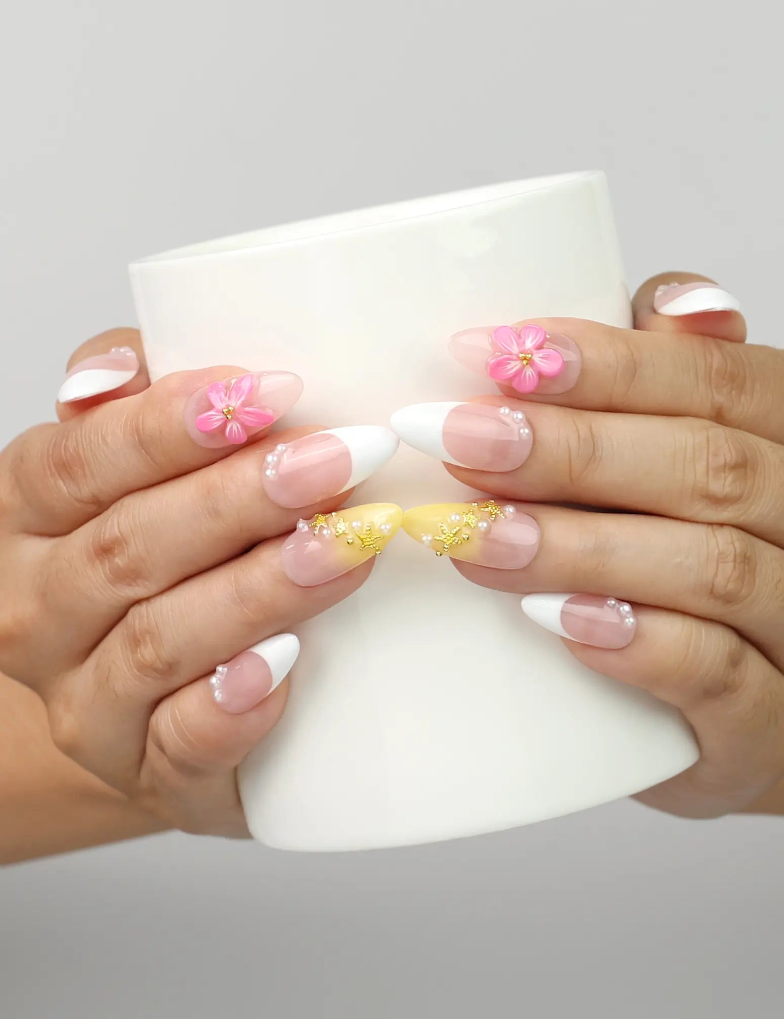 Model holding a cup while wearing Naillover Petal Dream handmade press on nails Singapore with 3D flower details.