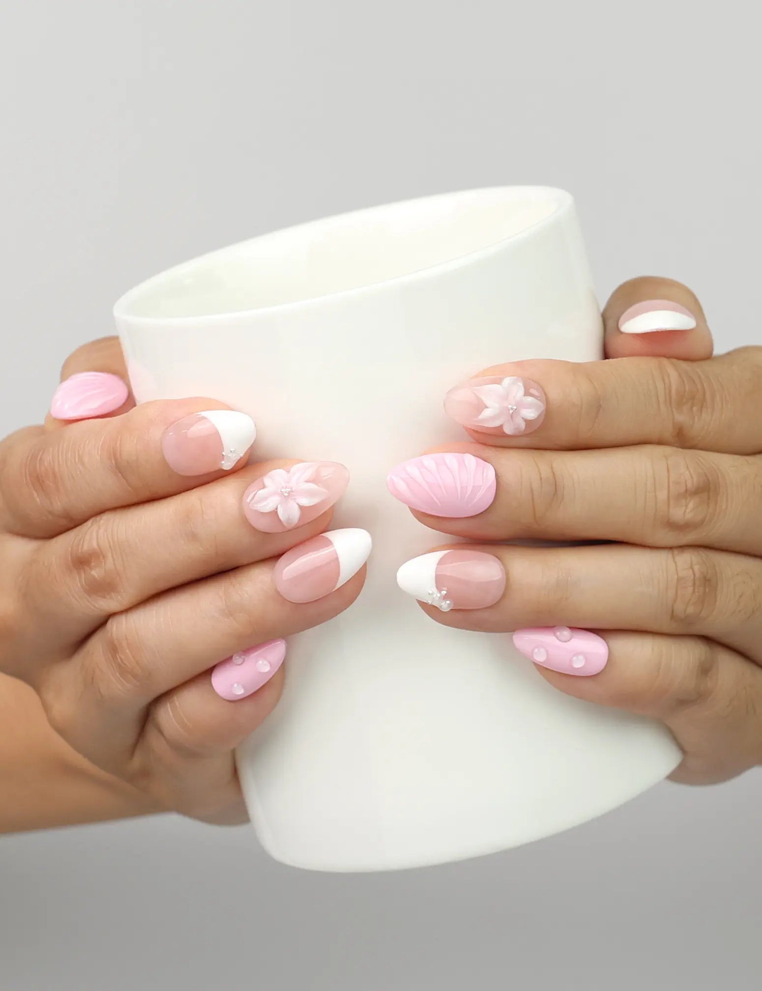 Model holding a cup while wearing Naillover Petal Grace handmade press on nails with floral accents.
