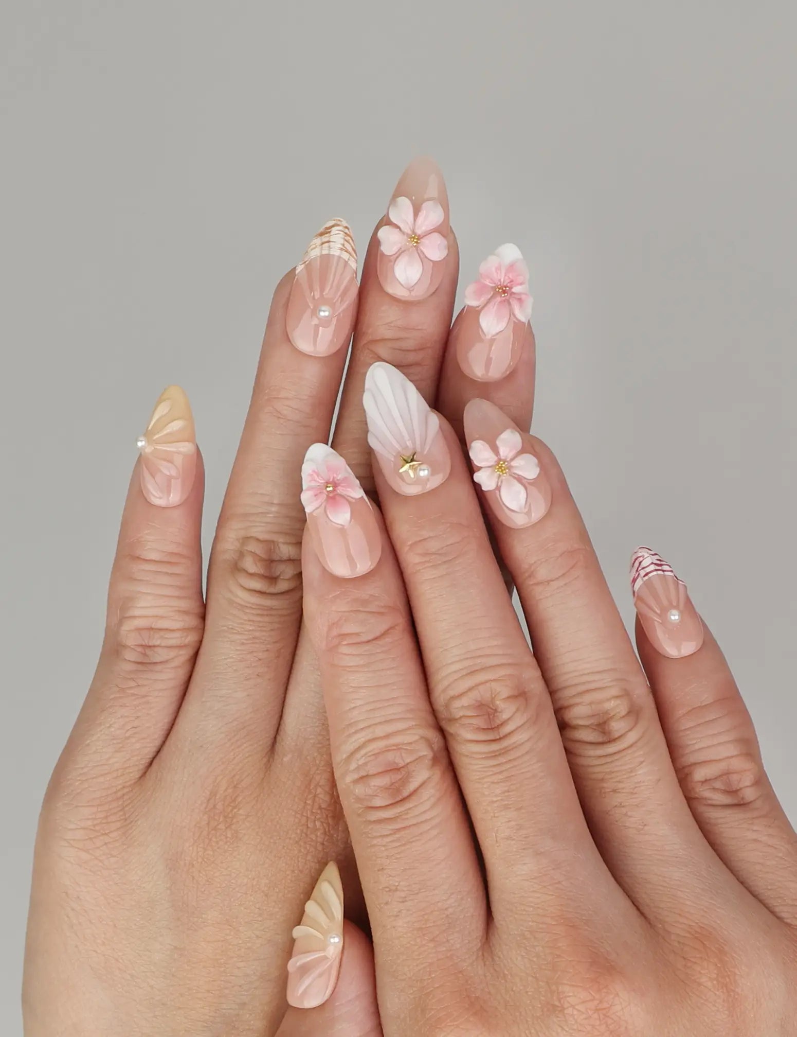 Naillover Pink Ocean 3D Floral handmade press on nails styled on hand with delicate flowers and pearlescent shell textures.