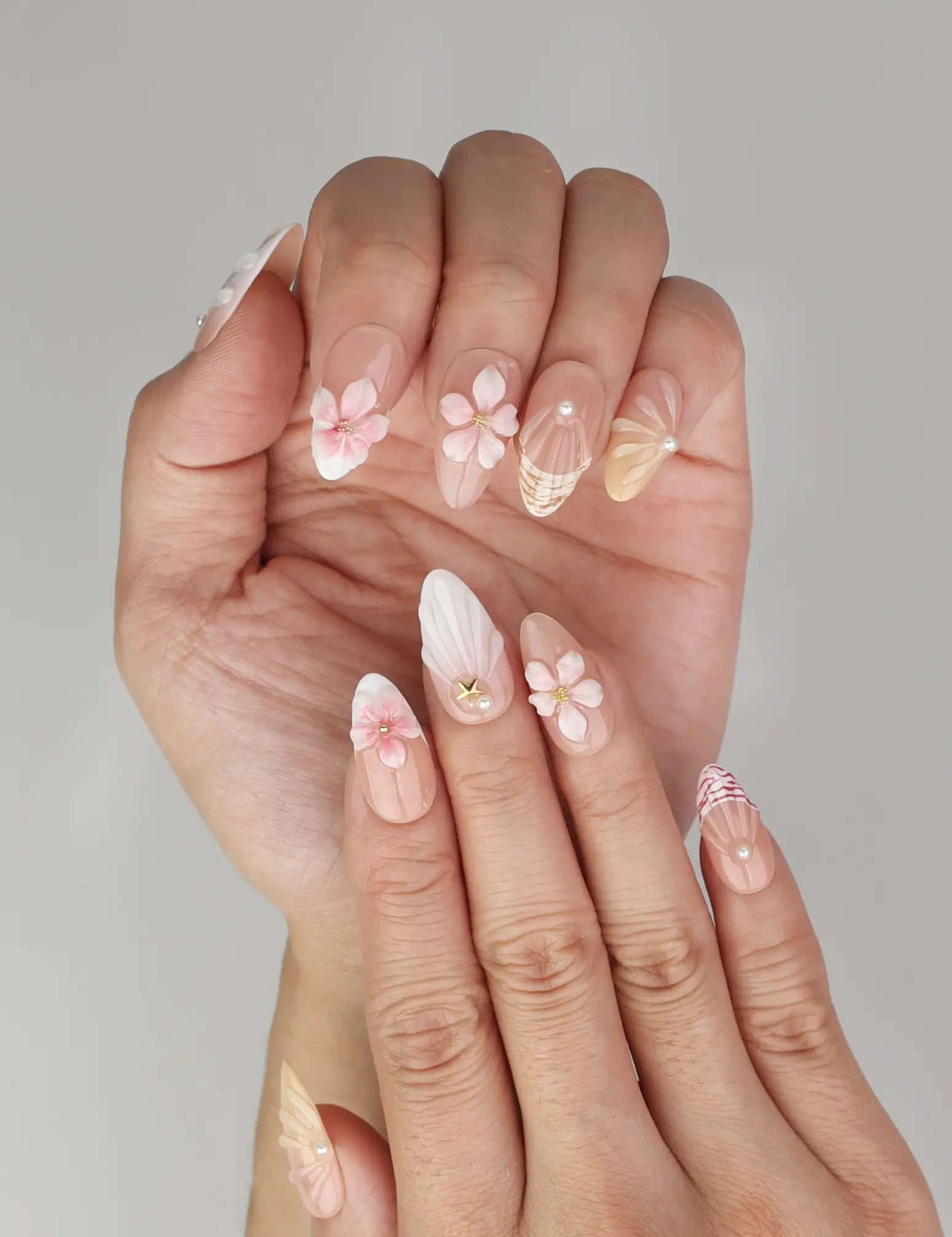 Elegant Naillover Pink Ocean 3D Floral Singapore press on nails on hand with pink florals, pearls, and star embellishments.