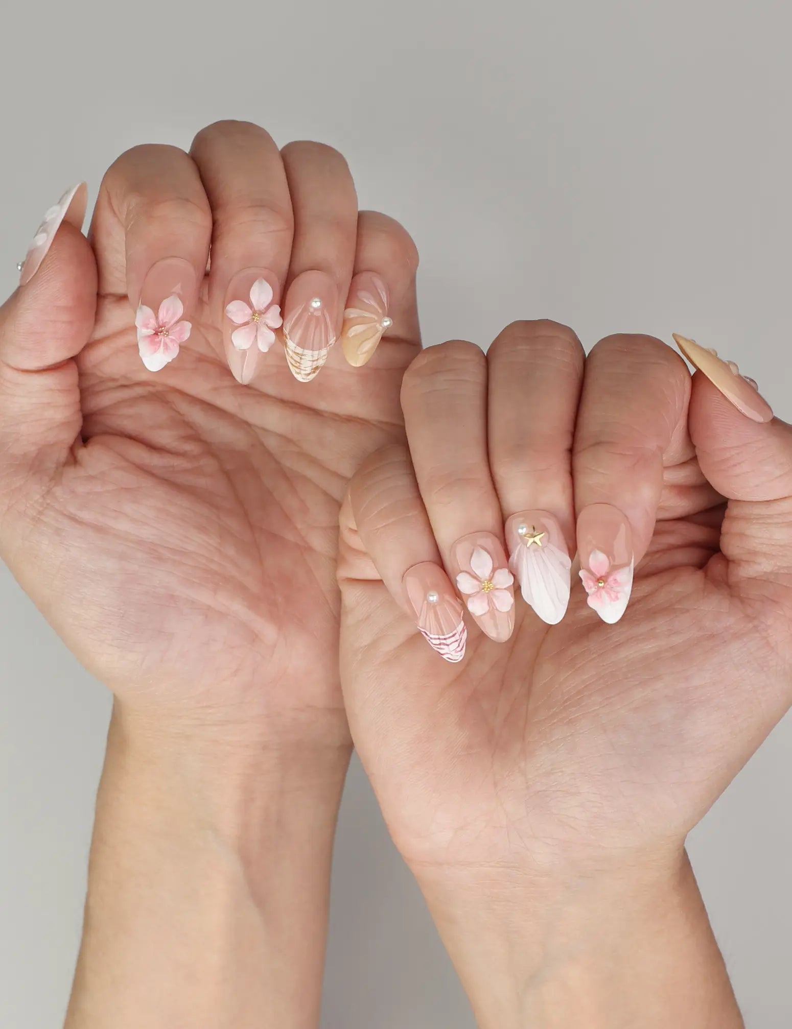 Close-up of Naillover Pink Ocean 3D Floral handmade press on nails worn on hand with gold stripes and 3D floral accents.