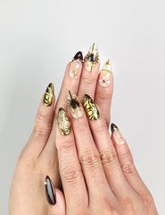 Model wearing Regal Radiance handmade Singapore press on nails in deep burgundy with gold accents and pearl embellishments