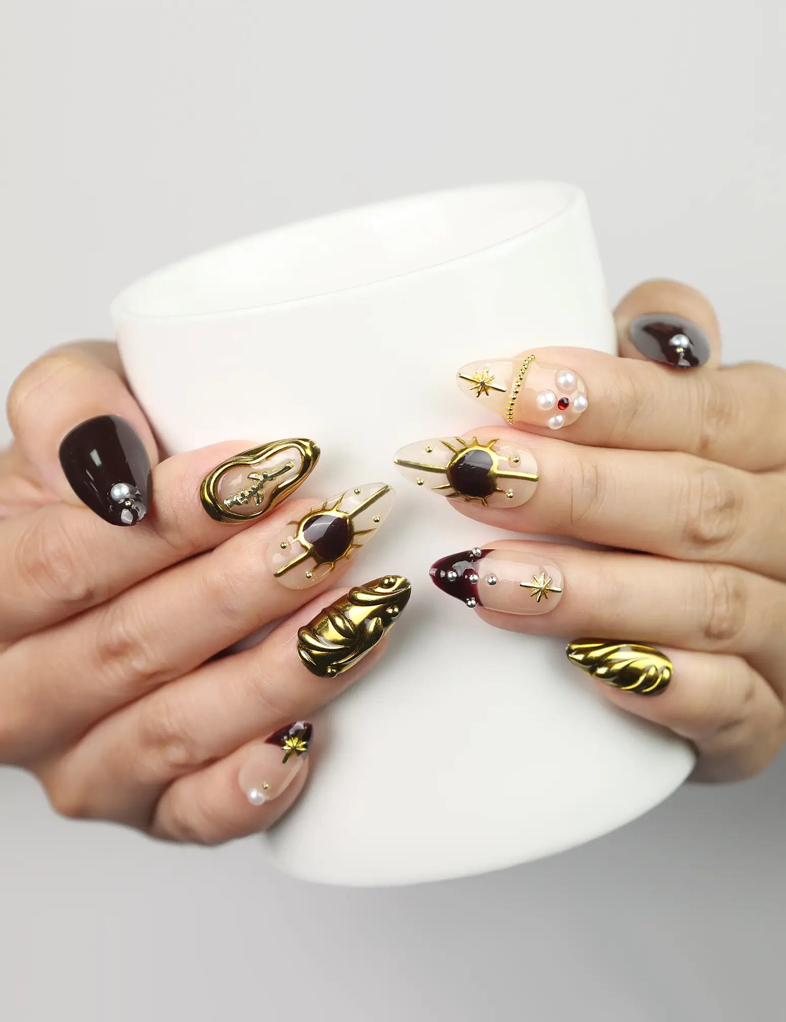 Regal Radiance Singapore press on nails by Naillover in burgundy and gold style, shown holding a coffee cup