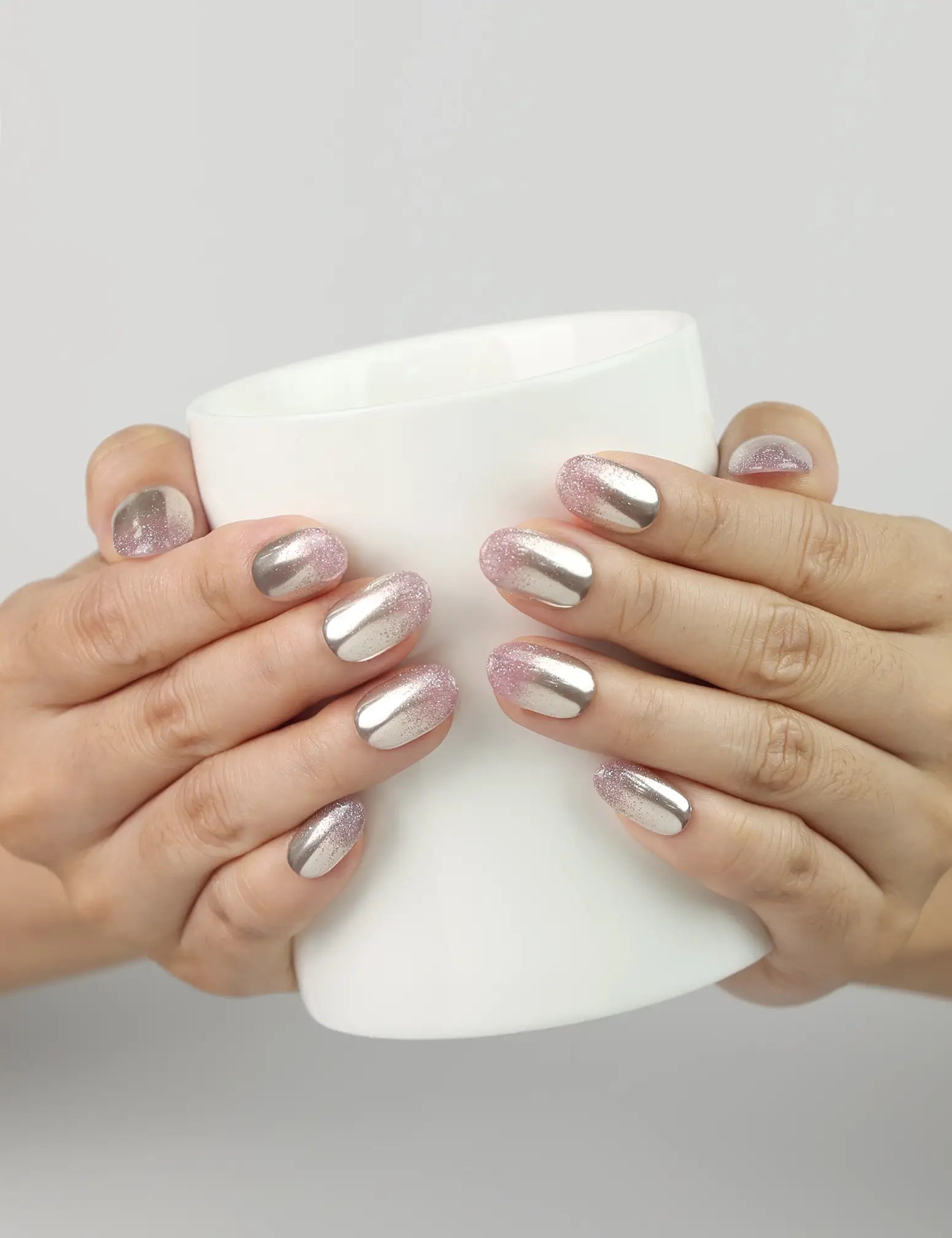 Model holding a cup while wearing Rose Haze Singapore press on nails in pink gradient shimmer for a romantic touch