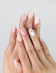 Hand model showing Shimmer Floral nails with shimmer accents and pink floral design under natural lighting.