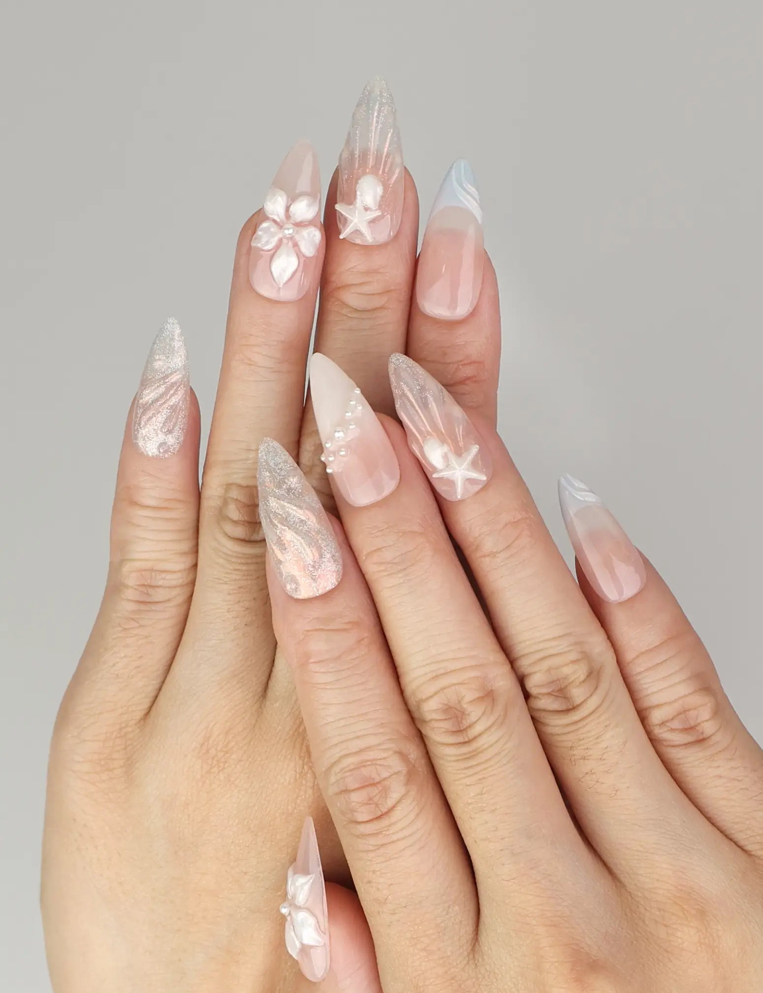 Naillover Shimmering Pearl And Floral Elegance handmade press on nails styled on hand with shell textures and floral accents.