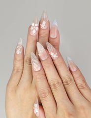 Naillover Shimmering Pearl And Floral Elegance handmade press on nails styled on hand with shell textures and floral accents.