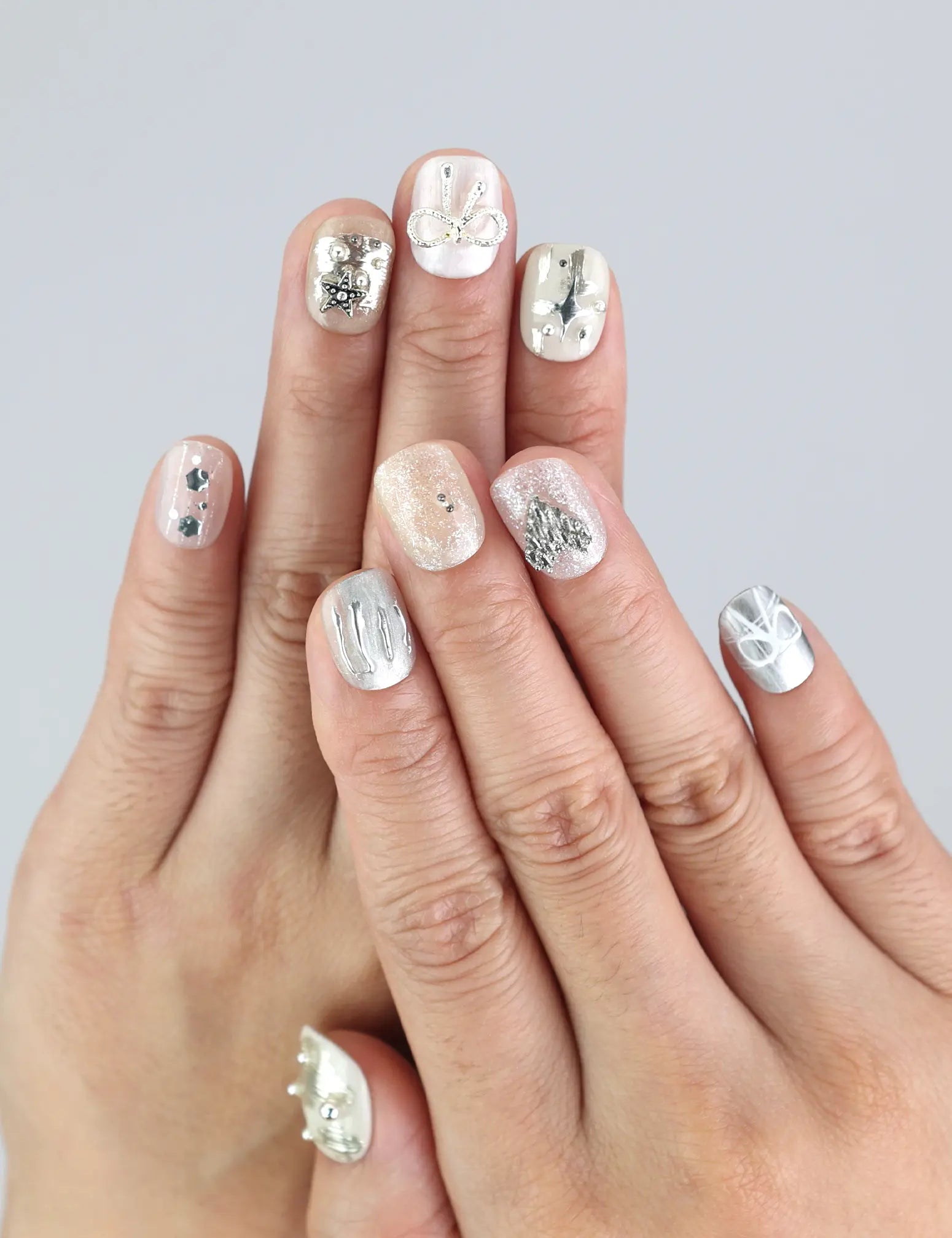 Model wearing Naillover Silver Bow nails—short white press on nails with silver bow accents for a chic, classic look.
