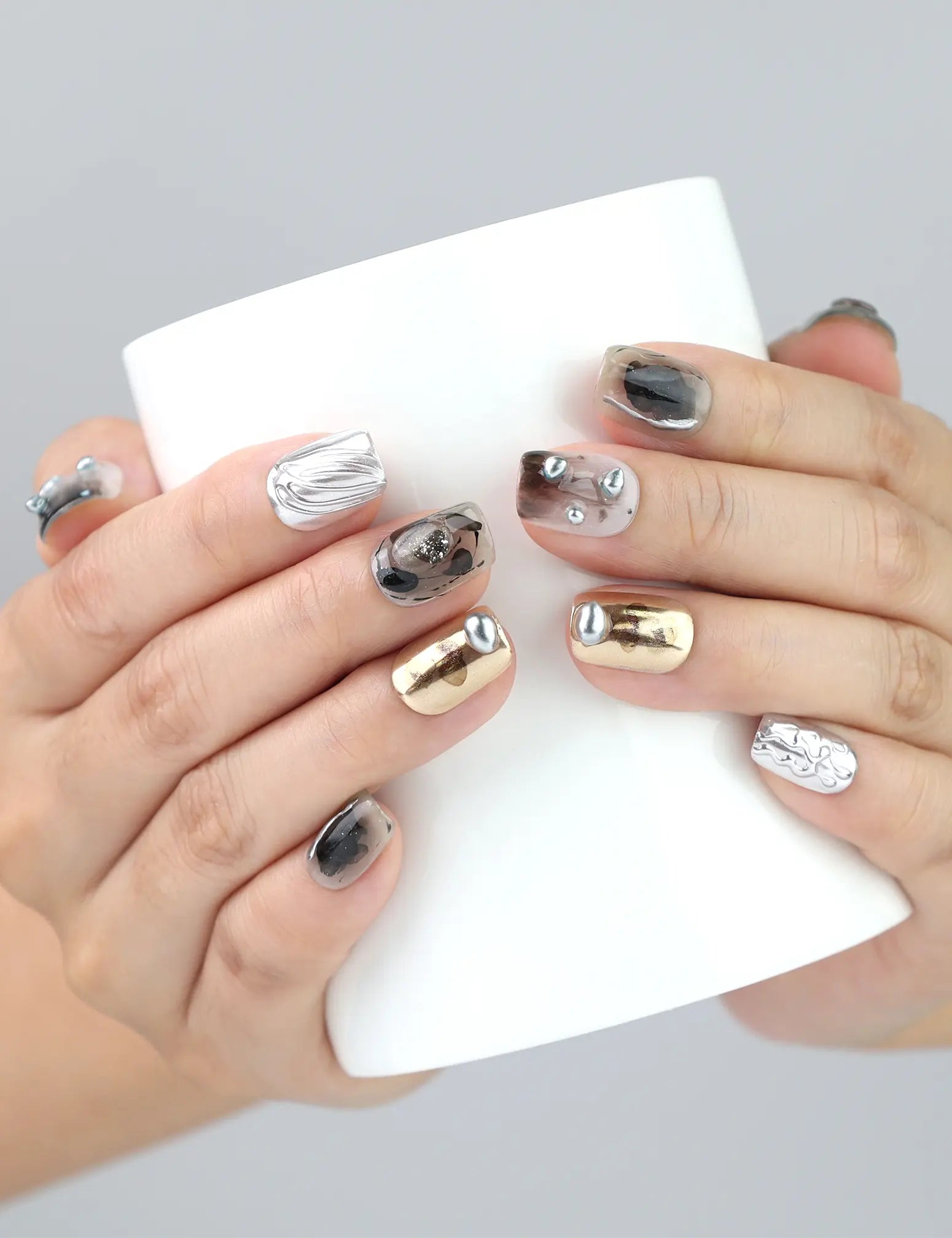 Hand holding drink with Naillover Smoky Metal Rush nails — Singapore press on nails with high-shine chrome and smoky texture, perfect for streetwear flair.