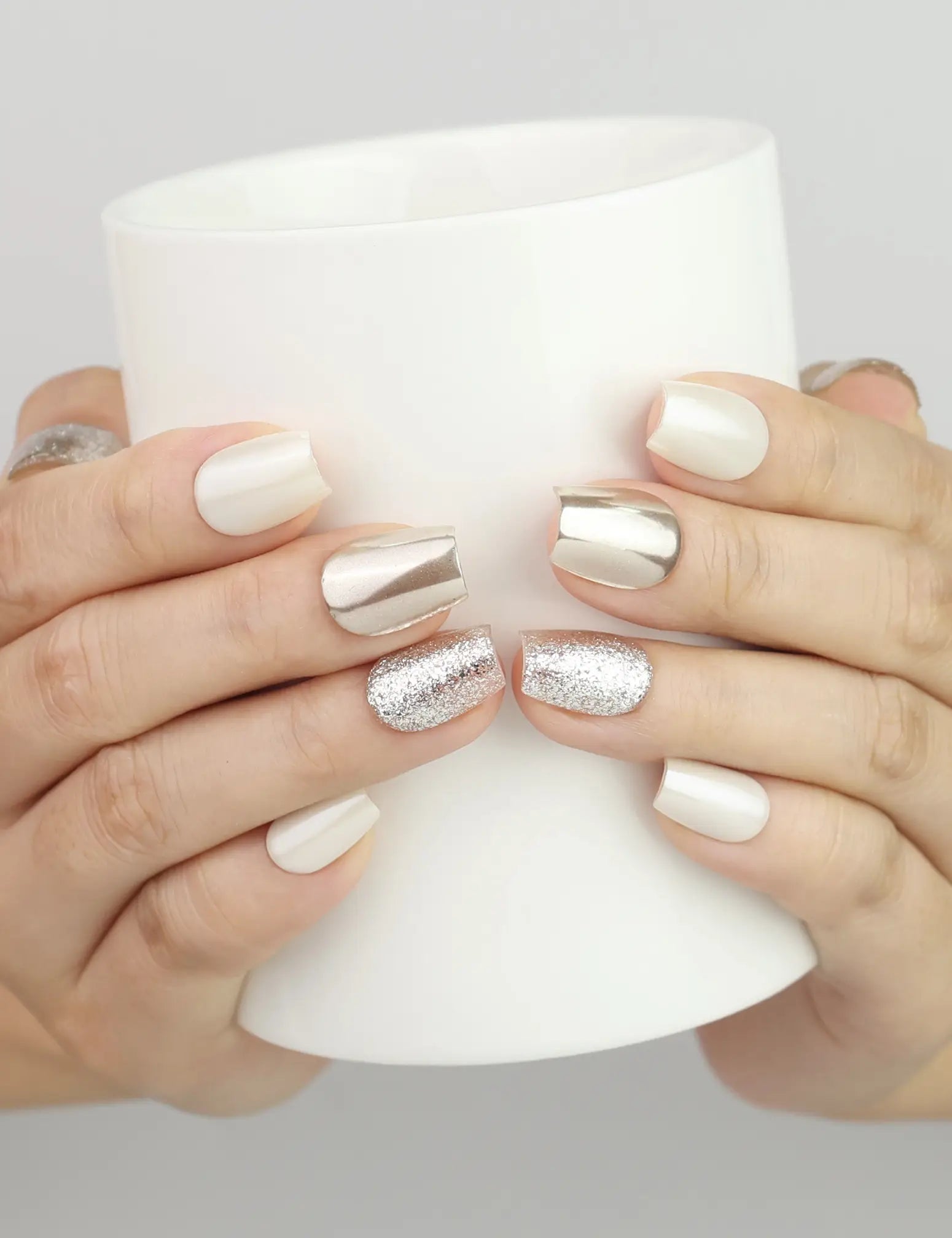 Hand holding a cup while wearing Naillover Sparkling Cream Singapore press on nails with cat eye shimmer