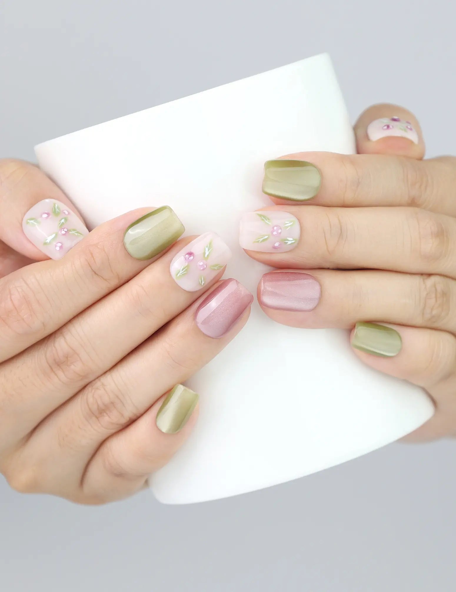 Naillover Spring Buds press on nails wrapped around a coffee mug—pastel hues and floral elements glisten in the light.