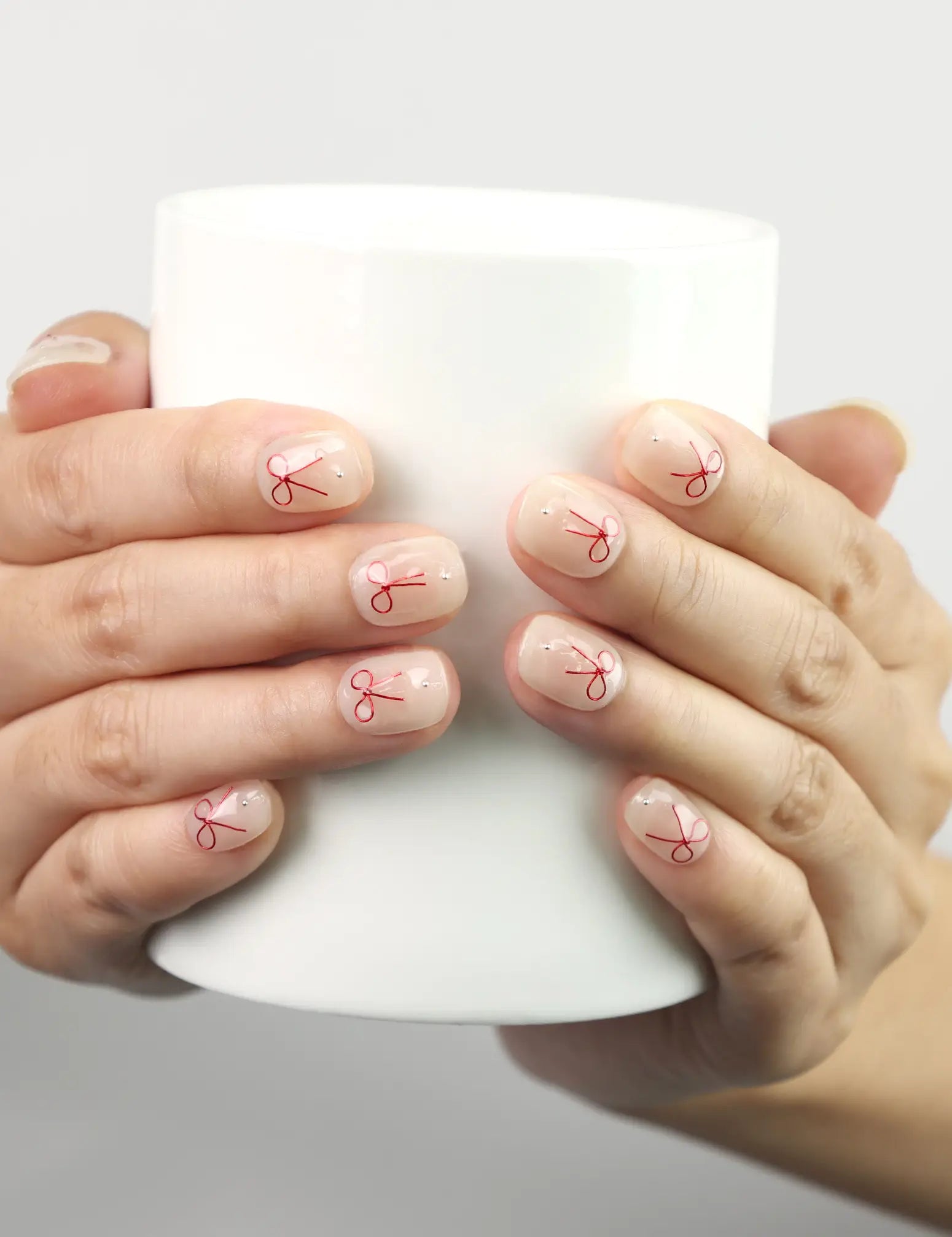 Naillover Sweet Bow handmade press on nails holding a cup, white nails with red bows, cute and simple nails Singapore