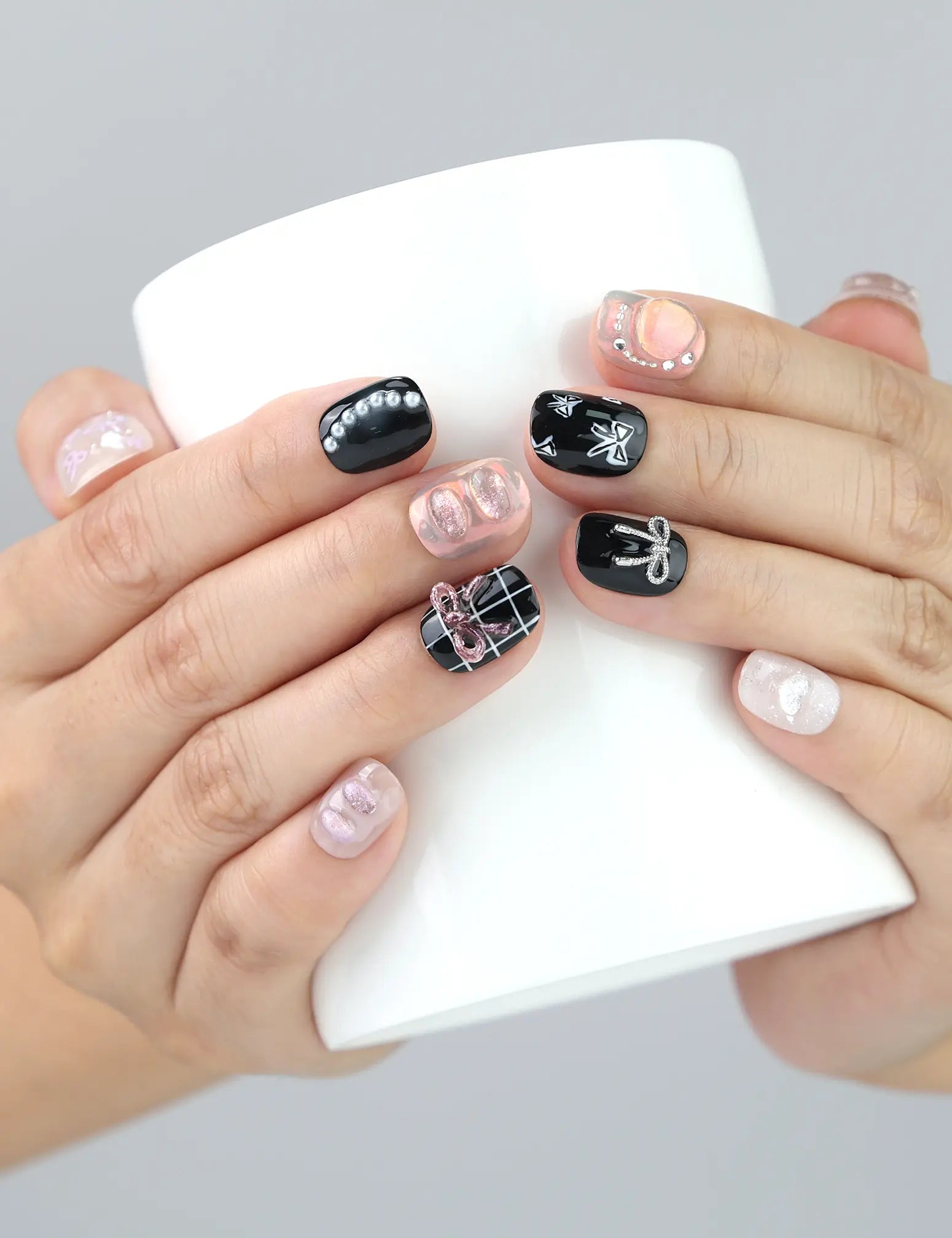 Sweet Goth handmade press on nails by Naillover shown gripping a coffee cup—black and white nails with silver shimmer for street-chic vibes.