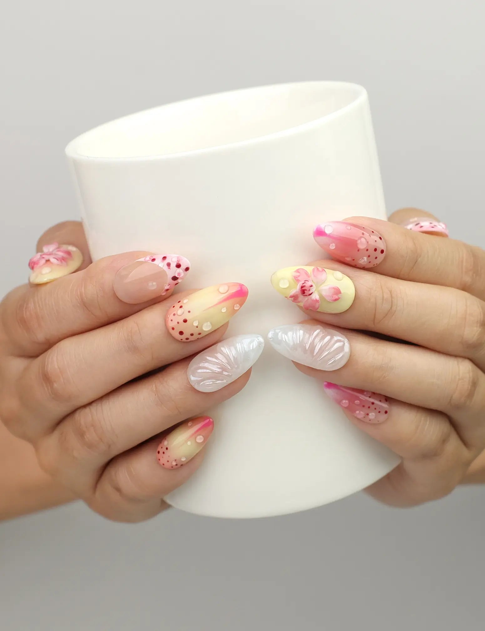 Naillover Sweet Pink Yellow 3D Floral Droplet press on nails SG shown while holding a cup, with floral and dotted embellishments