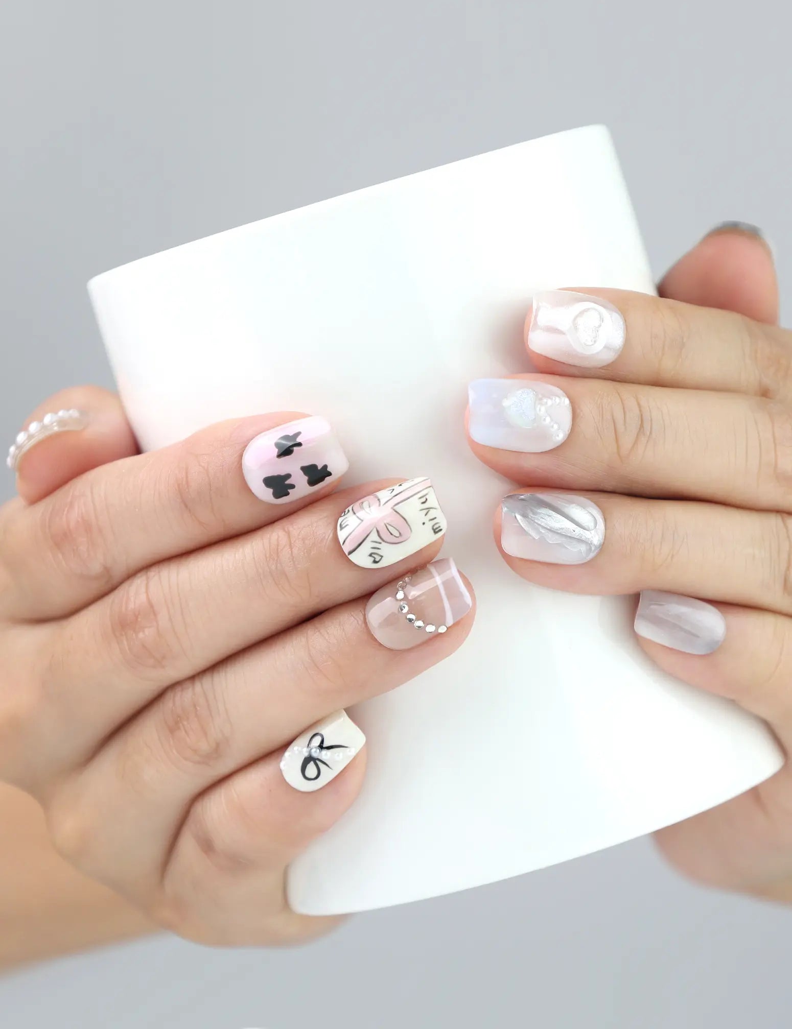 Model holding a cup while showcasing Sweet Ribbon handmade press on nails in soft lavender and crystal design.
