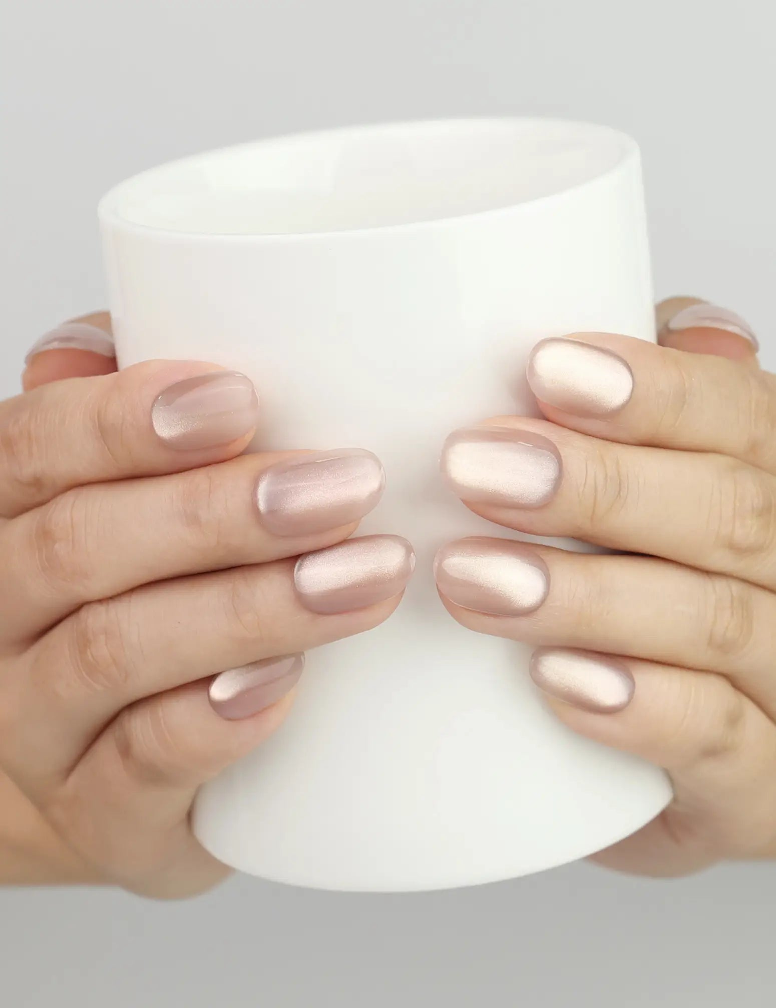 Hand holding a cup with Naillover Tender Shine Singapore press on nails and pearlescent shimmer
