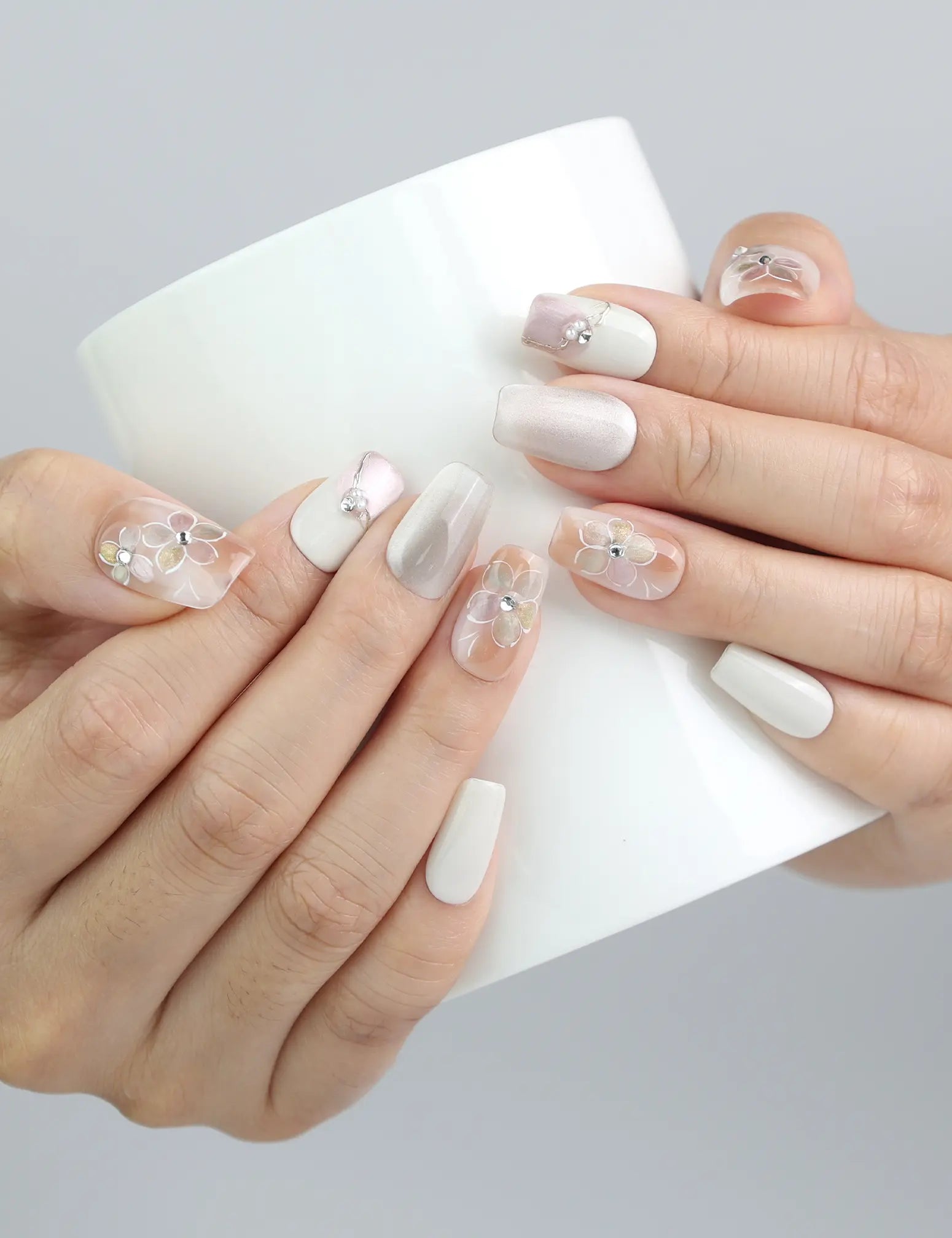 Hand holding a cup while wearing Twilight Singapore press on nails, blending romantic tones and subtle gold-flower designs.