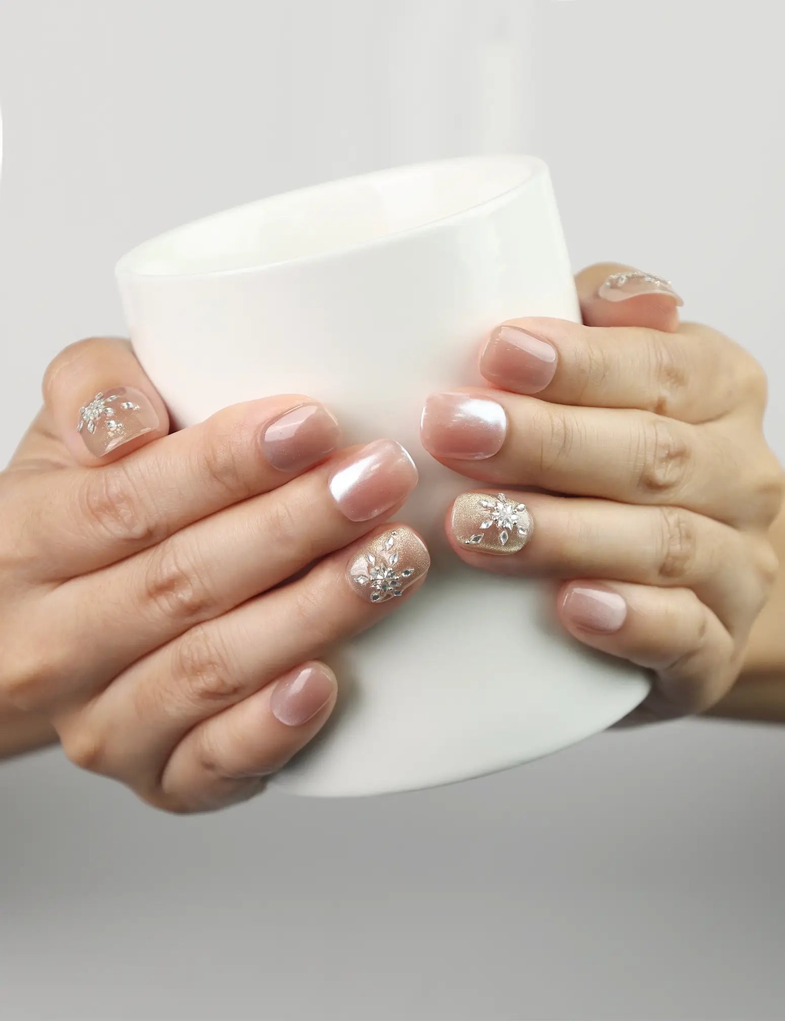 Warm Petal Singapore press on nails by Naillover in pink-to-white ombre with crystals, shown holding a coffee cup