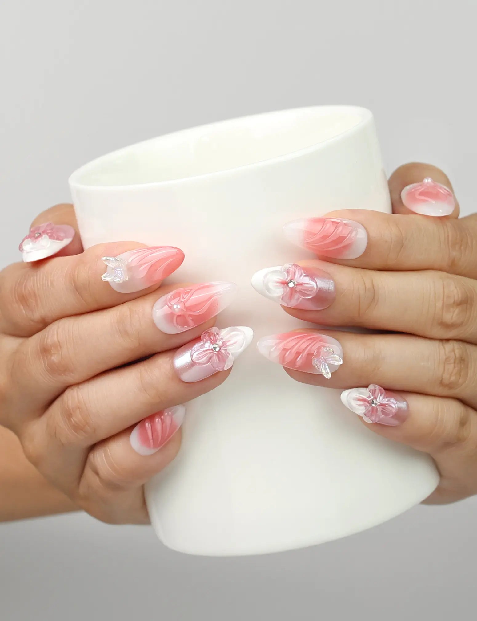 Model holding a cup while wearing Naillover Whisper of Wisteria handmade press on nails Singapore with butterfly and floral embellishments.