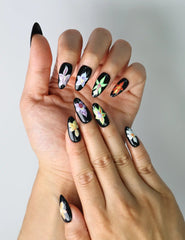 Close-up of elegant floral nails featuring deep black polish and painted iris petals for a moody, romantic look