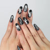 Hand model wearing black oval-shaped press-on nails with silver ombré fade and 3D butterfly crystal charms