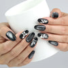 Hand holding a cup, showcasing Naillover’s glamorous black nails with crystal butterflies and silver fade details