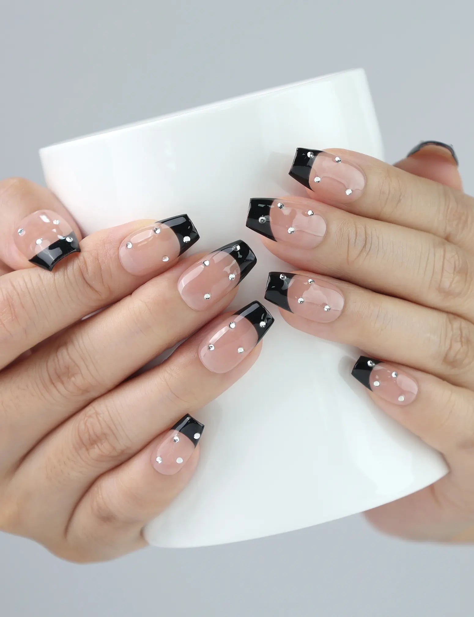 Woman holding coffee cup while wearing Nude Edge Singapore press on nails by Naillover, showcasing stylish office-to-evening look.