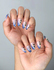 Side view of ocean-inspired almond nails with layered blue gradients and blooming peony-style florals