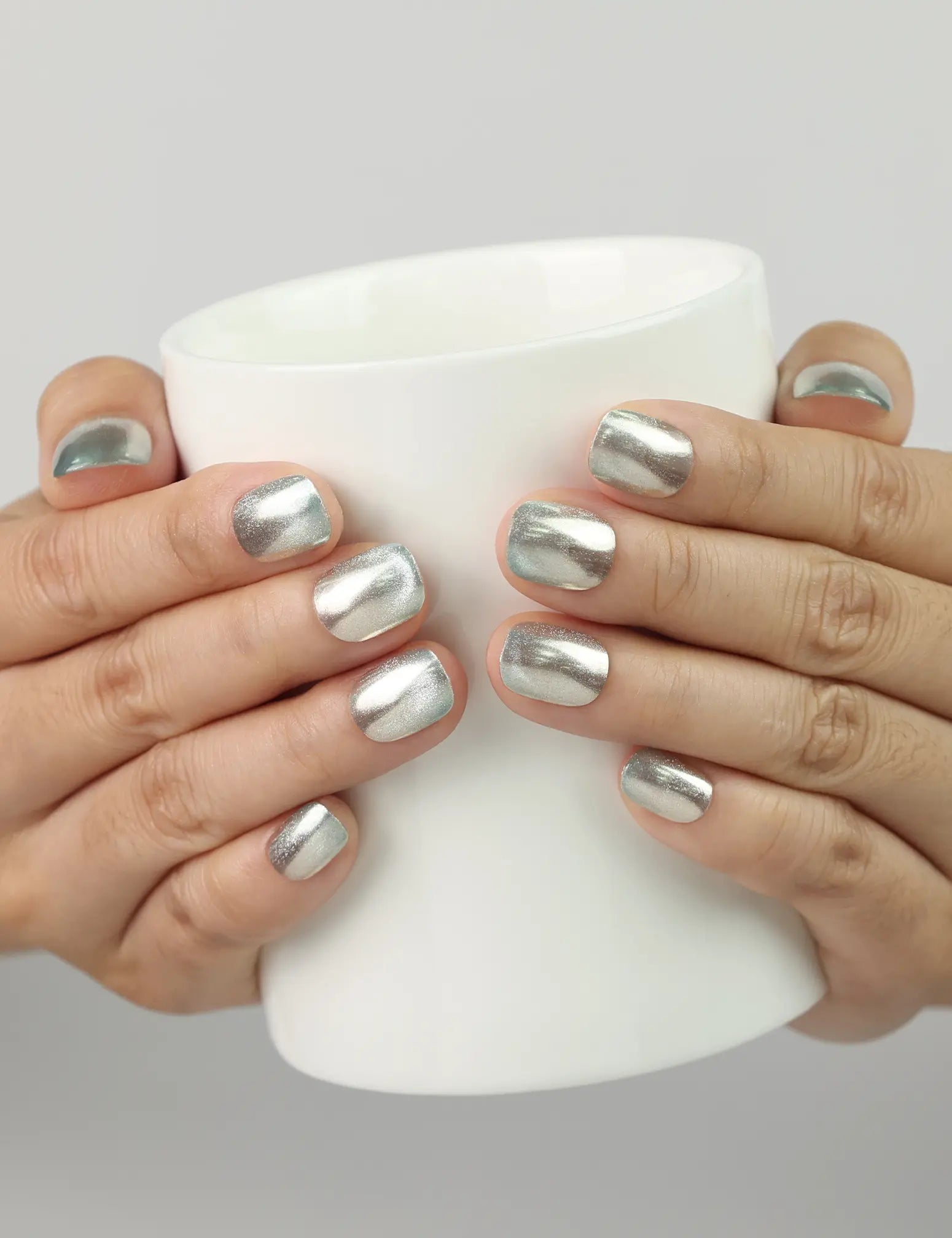 Hand holding cup with Ocean Breeze handmade press on nails, blue shimmer finish perfect for summer outings.
