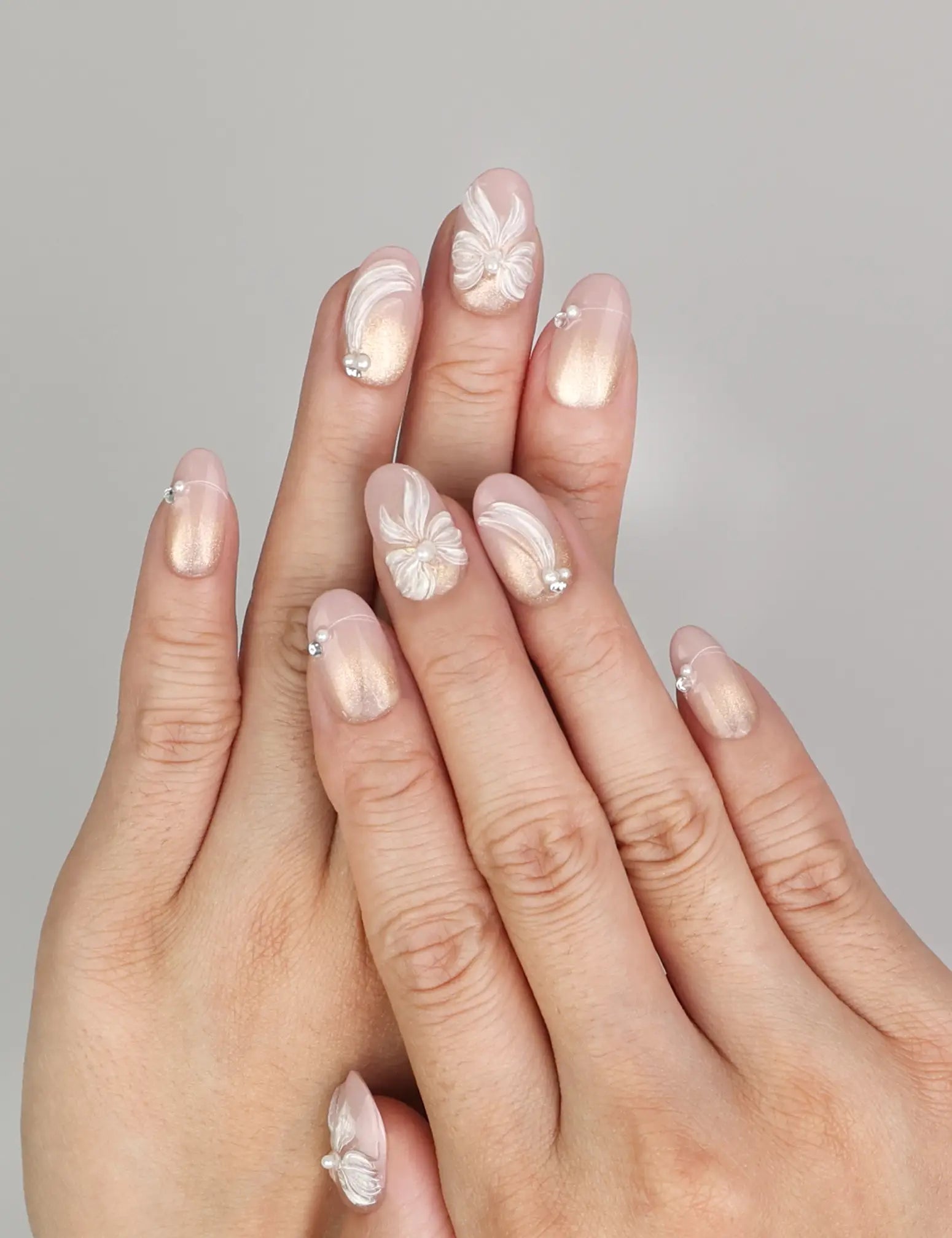Hand wearing Naillover Pearl Bloom Bronze handmade press on nails with floral bronze design, shimmering accents, and rhinestone details.