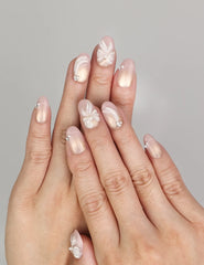 Hand wearing Naillover Pearl Bloom Bronze handmade press on nails with floral bronze design, shimmering accents, and rhinestone details.