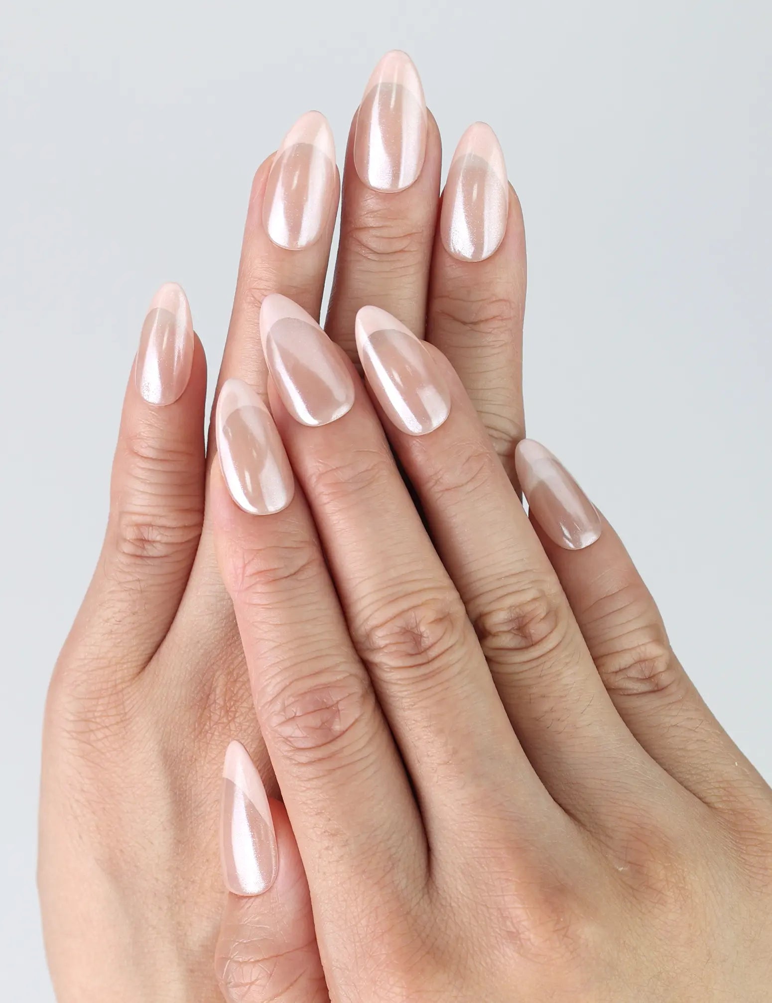 Hand model wearing handmade pink almond press-on nails in a natural rose petal tone with high-gloss finish