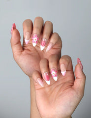 Side view of feminine almond nails with glossy base and dimensional flower embellishments in a romantic palette
