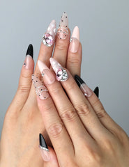 Hand model wearing pink press-on nails with soft ombré base and bold black zebra print details