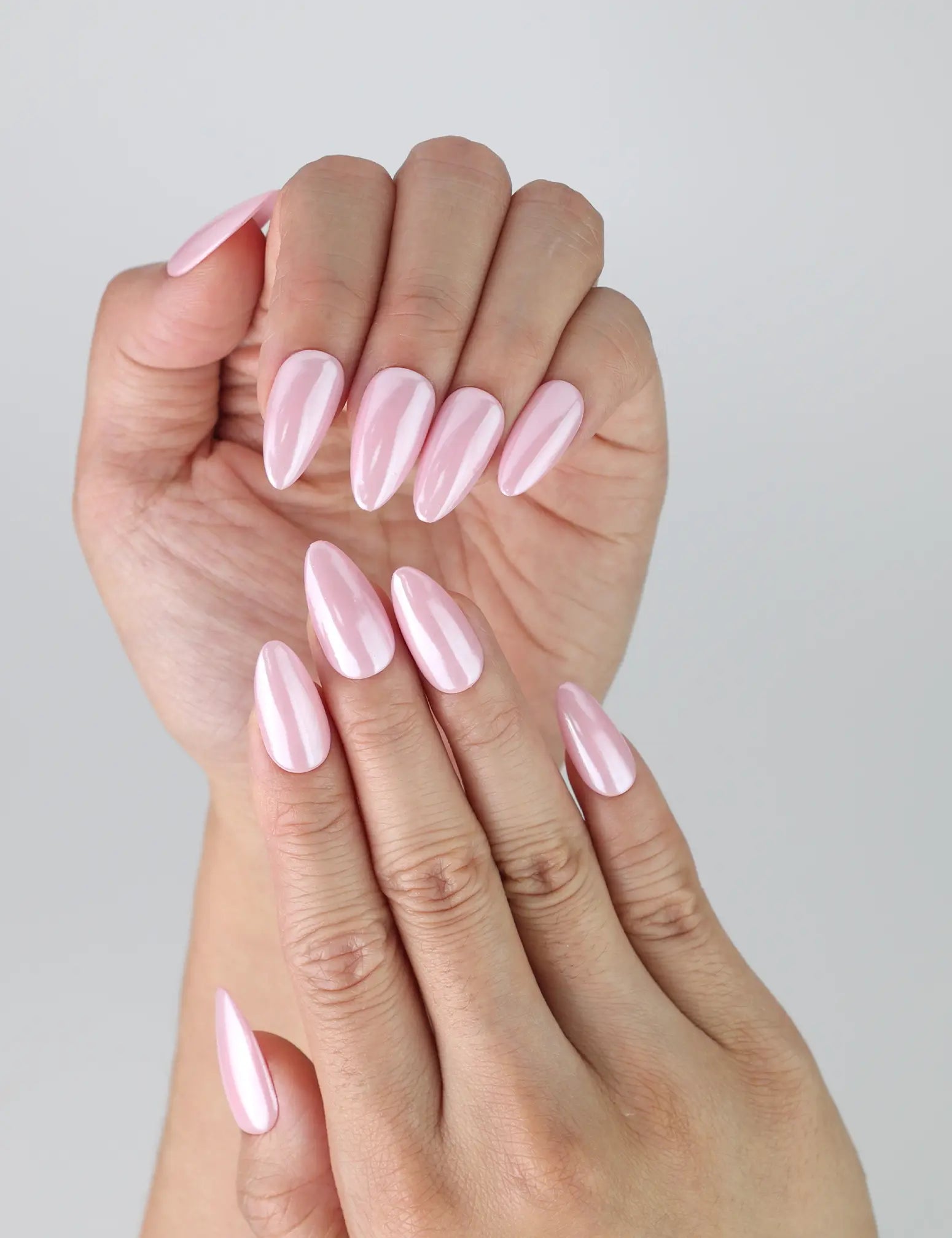 Close-up of pink glossy nails in short almond shape, showcasing a natural, understated manicure